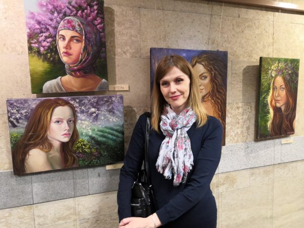 Svetlana Belova against the background of her work at the exhibition of paintings